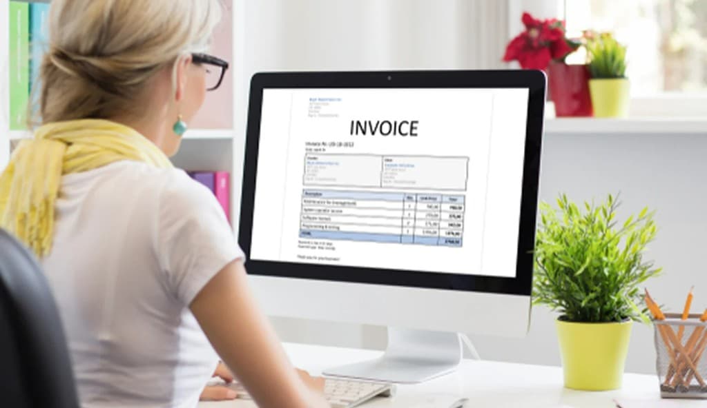 Workspace with laptop, notebook, and coffee for creating a digital invoice